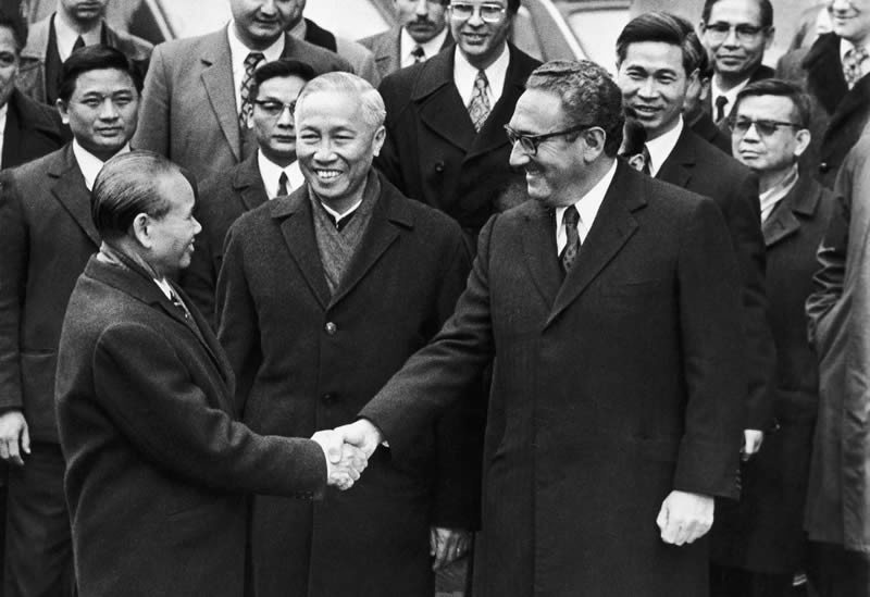 Xuân Thủy bắt tay H. Kissinger. Dứng giũa là Lê Đức Thọ, sau lưng Kissinger là Nguễn Co Thạch. Nguồn:  http://nation-building.jeremisuri.net