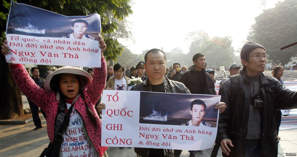 Người biểu tình xuống đường tưởng niệm 40 năm trận hải chiến Hoàng Sa tại Hà Nội với biểu ngữ ‘Tổ quốc ghi công, đời đời nhớ ơn anh hùng Ngụy Văn Thà và đồng đội’. Nguồn: Reuters.