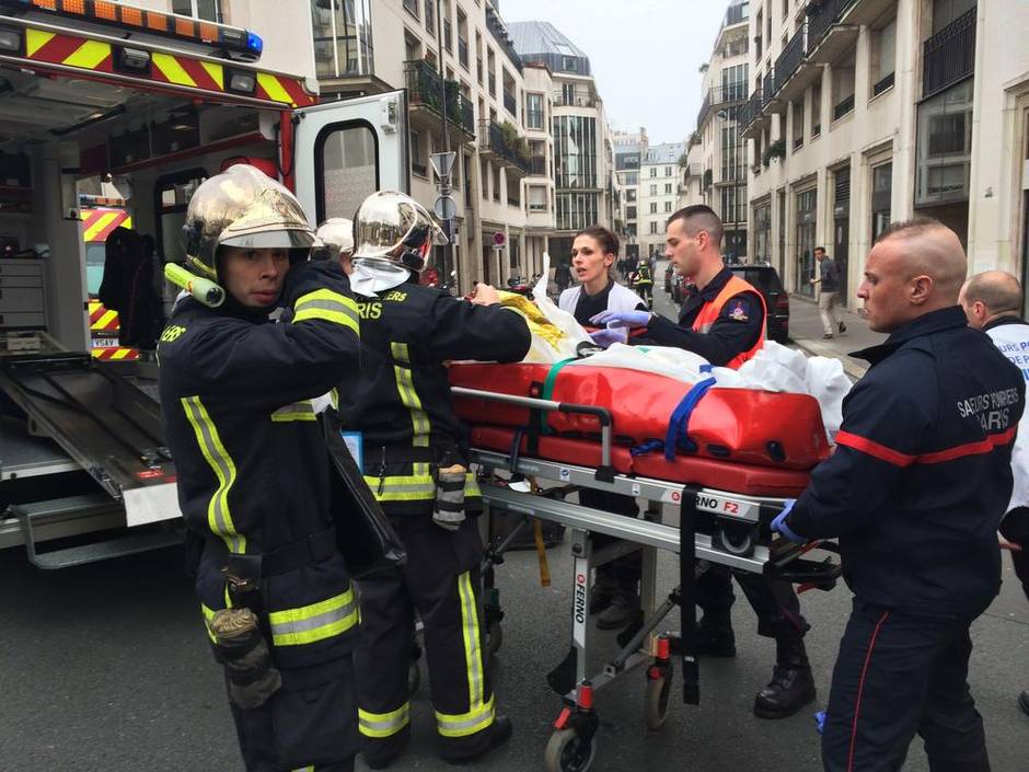 Nhân viên cứu hỏa mang theo một người đàn ông bị thương trên cáng ở phía trước của văn phòng Charlie Hebdo. (Philippe Dupeyrat / AFP / Getty Images) 