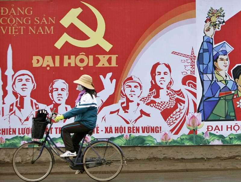 Một cô gái đi xe đạp qua một tấm bích chương quảng bá cho Đại hội toàn quốc lần thứ 11 của Đảng Cộng sản Việt Nam vào tháng Giêng năm 2011. Đại hội Đảng lần thứ 12 sắp tới, sẽ được tổ chức vào đầu năm 2016, sẽ xác định tư thế kinh tế và an ninh mới của Việt Nam. Nguồn ảnh: AAP 