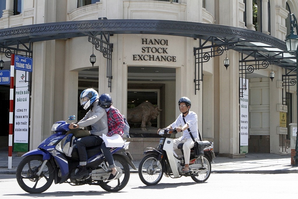 Người trên xe máy đi xe qua trụ sở sàn giao dịch chứng khoán tại Hà Nội, Việt Nam, ngày 26 tháng sáu năm 2015. Nguồn: REUTERS Hà Nội / Stringer