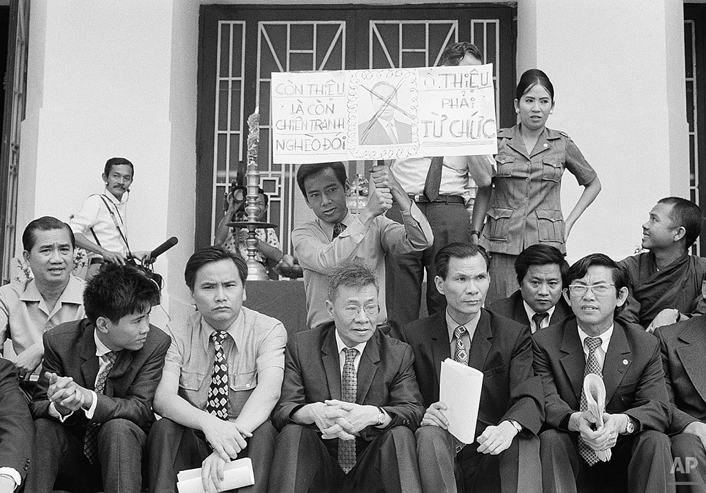 Opposition deputies stage a 24-hour sit-in hunger strike on the steps of the national assembly to protest what they term ?The corrupt, inefficient and oppressive administration? of President Nguyen Van Thieu in Saigon, Feb. 10, 1975. One deputy hoists a placard with defaced photo of Thieu which says: ?If Thieu still remains in power, there will still exist war, poverty and starvation. Mr. Thieu must resign.? (AP Photo/Ut)